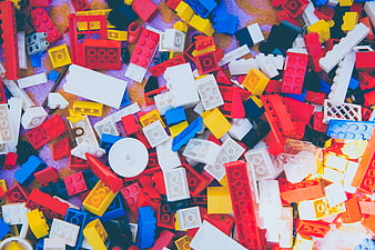 Colorful pile of mixed plastic building blocks on textured background