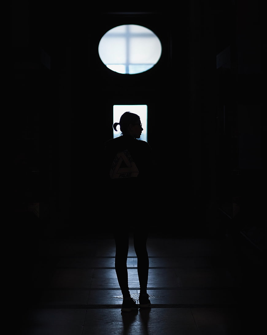 Silhouette of woman standing in dark hallway with light