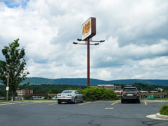 Parking Lot with Cars and Mountain View Under Cloudy Sky