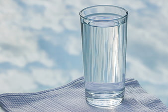 Glass of water on blue cloth with sky background