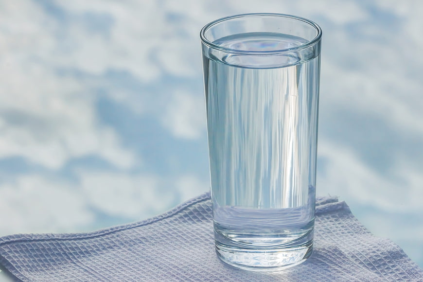 Glass of water on blue cloth with sky background