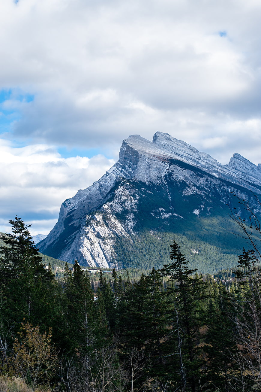 Majestic Rocky Mountain Peak with Forest and Clouds