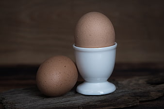 Brown Eggs in White Cup on Rustic Wood