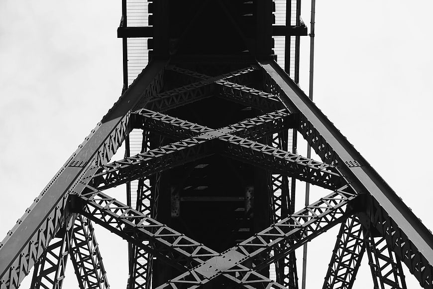 Low angle black and white view of steel bridge truss structure