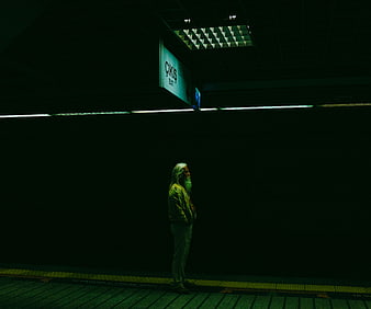 Lonely old man standing alone in dark subway station