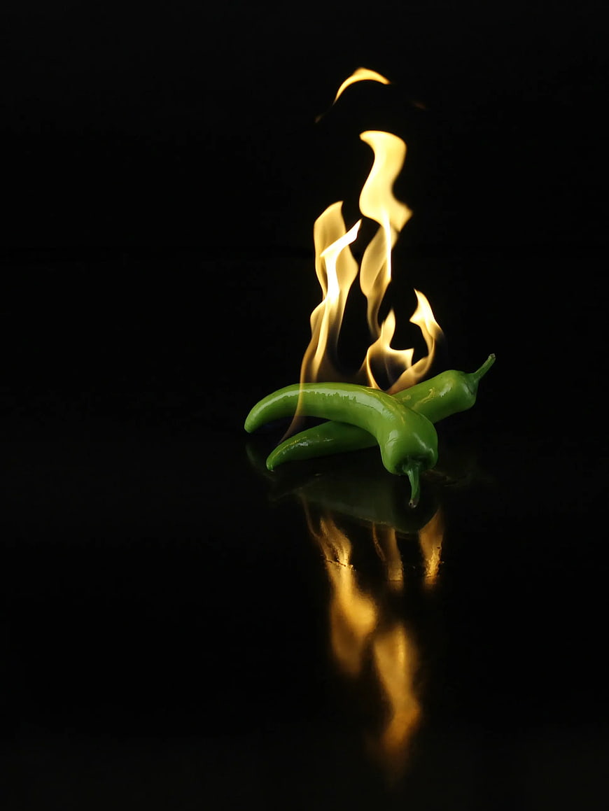 Green Chilies with Fire on Black Background
