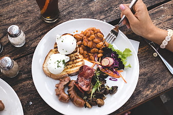 Overhead view of hearty brunch plate with poached eggs, beans, and bacon