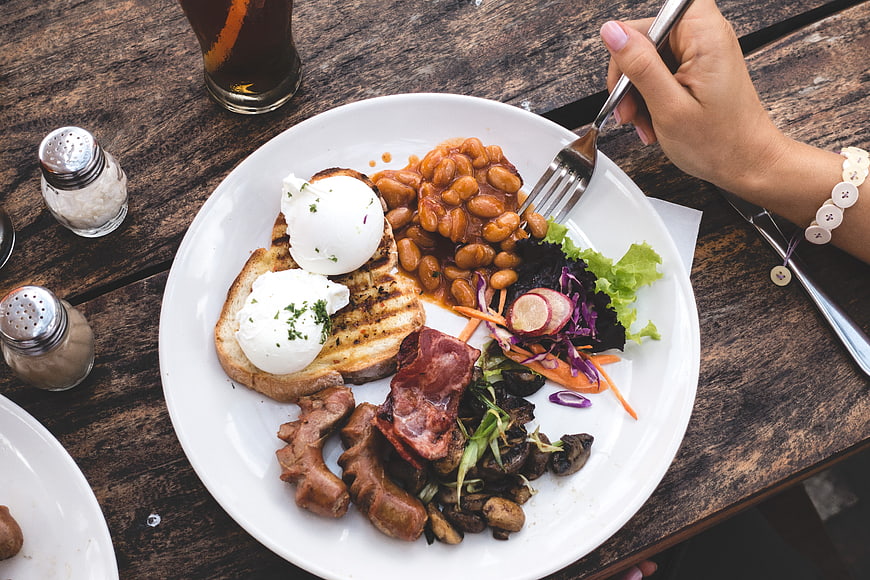 Overhead view of hearty brunch plate with poached eggs, beans, and bacon