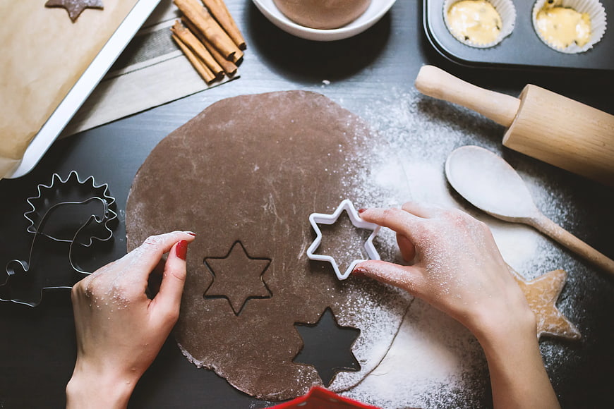 Hands Cutting Star-Shaped Gingerbread Cookies with Cookie Cutter