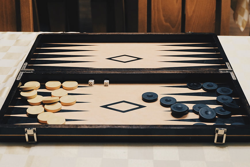 Open wooden backgammon board with dice and checkers on table