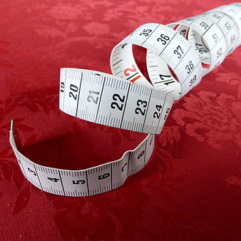 White measuring tape on red textured fabric background