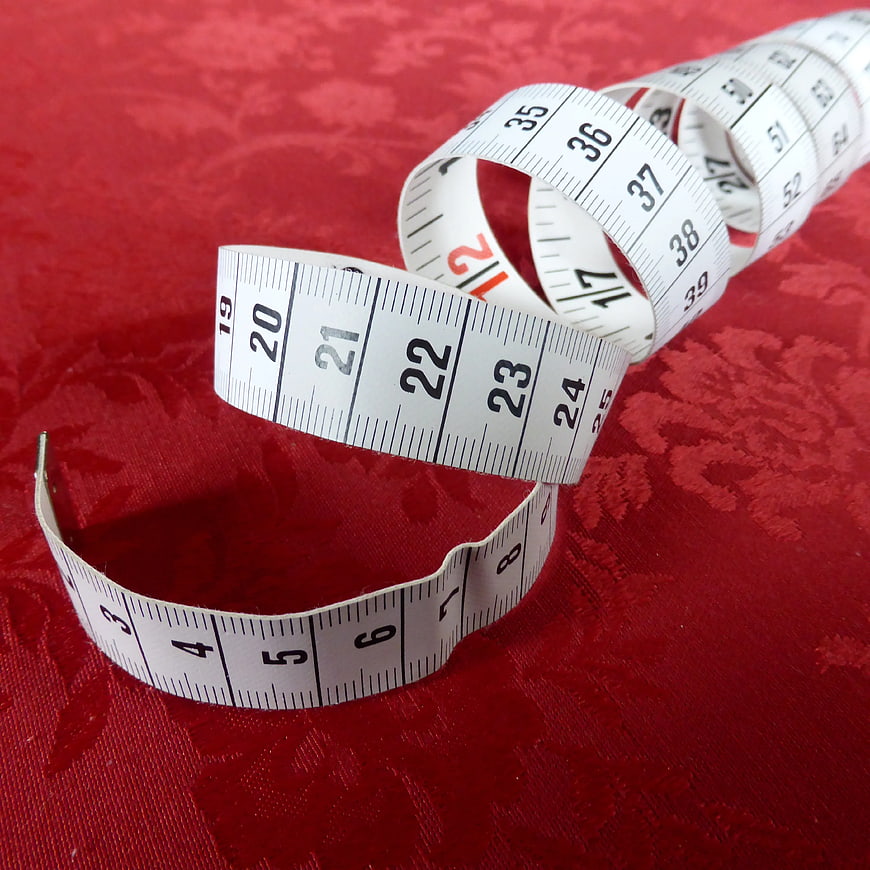 White measuring tape on red textured fabric background