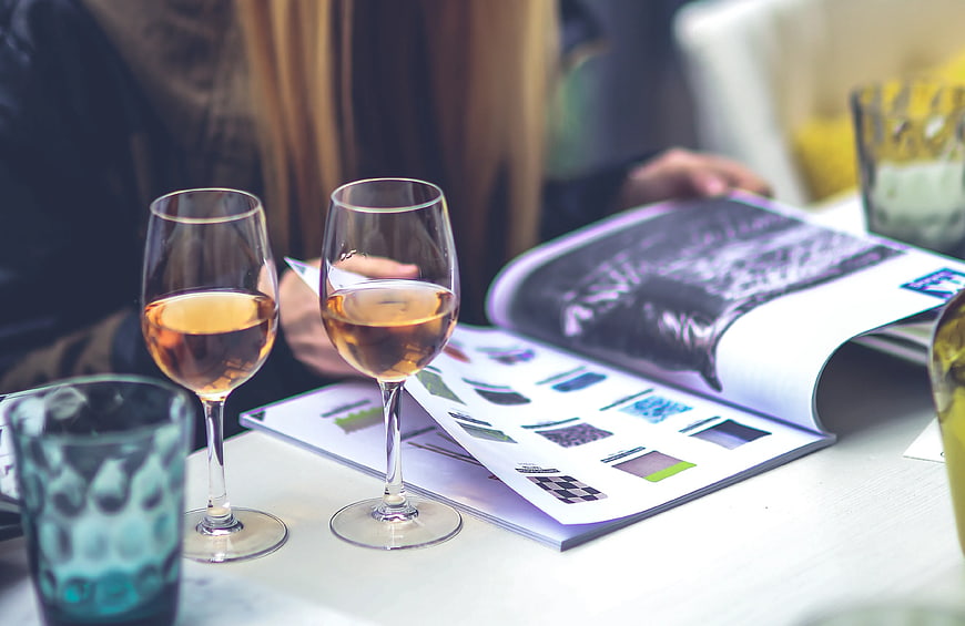 Two glasses of white wine and magazine on table