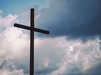 Silhouette of a wooden cross against a dramatic cloudy sky