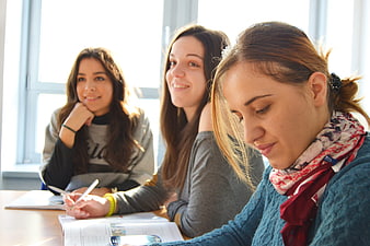 Three female students studying together in a bright classroom