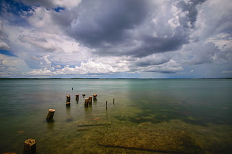 Dramatic Seascape with Weathered Wooden Posts in Calm Water