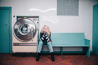 Blonde woman sitting on bench in retro laundromat