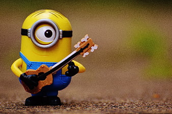 Cute Minion Toy Playing Guitar On Textured Ground