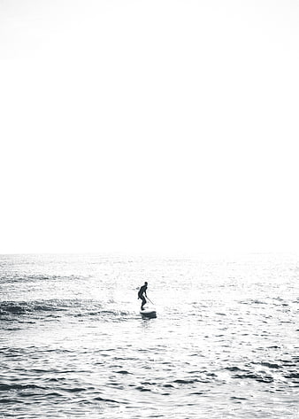 Silhouette of paddleboarder on calm ocean water