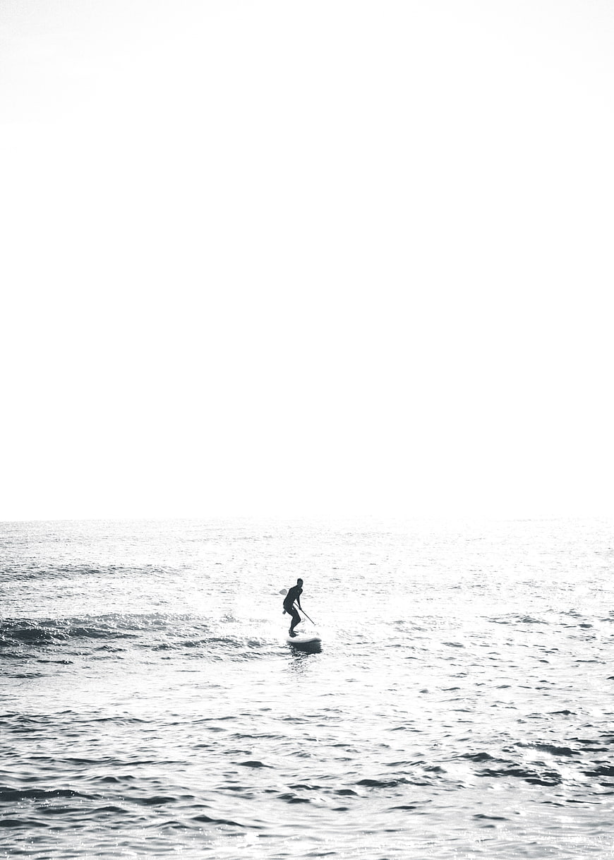 Silhouette of paddleboarder on calm ocean water