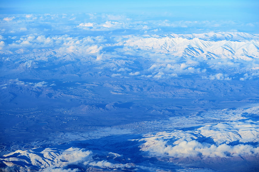 Aerial View of Snow-Capped Mountains and Clouds