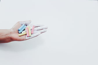 Hand holding pastel chalks on white background