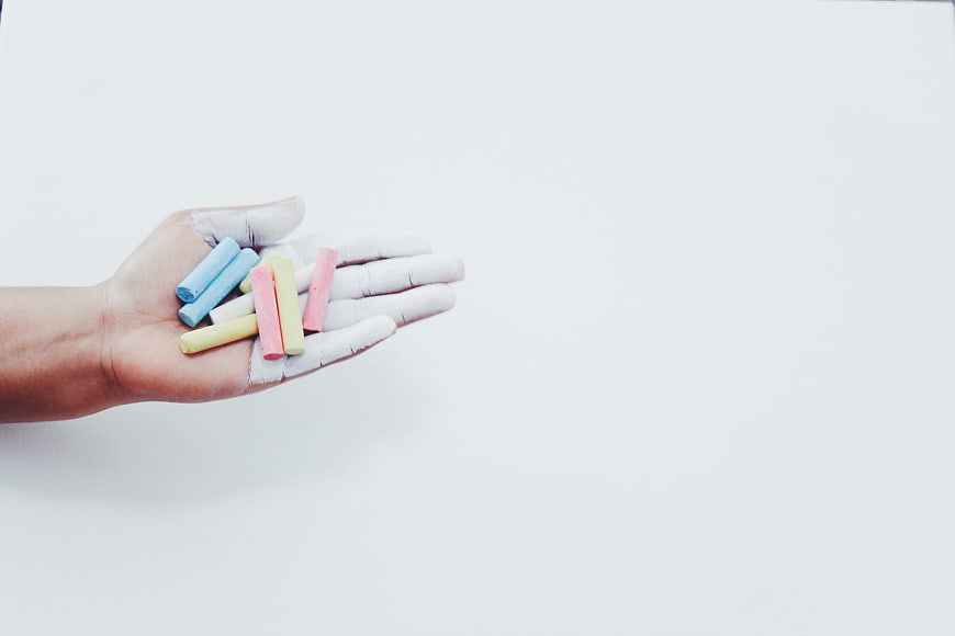 Hand holding pastel chalks on white background