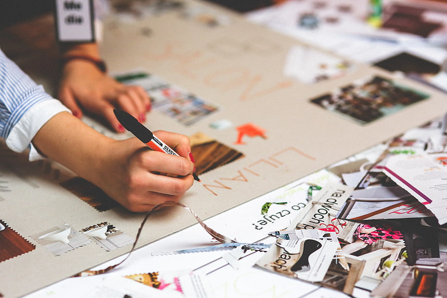 Designer creating mood board with magazine cutouts and marker