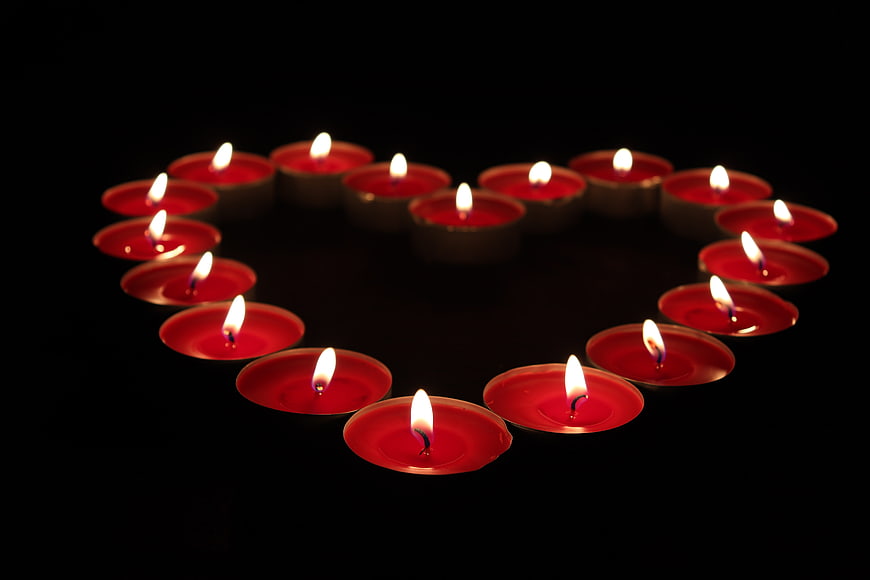 Red tea light candles arranged in a heart shape on black background
