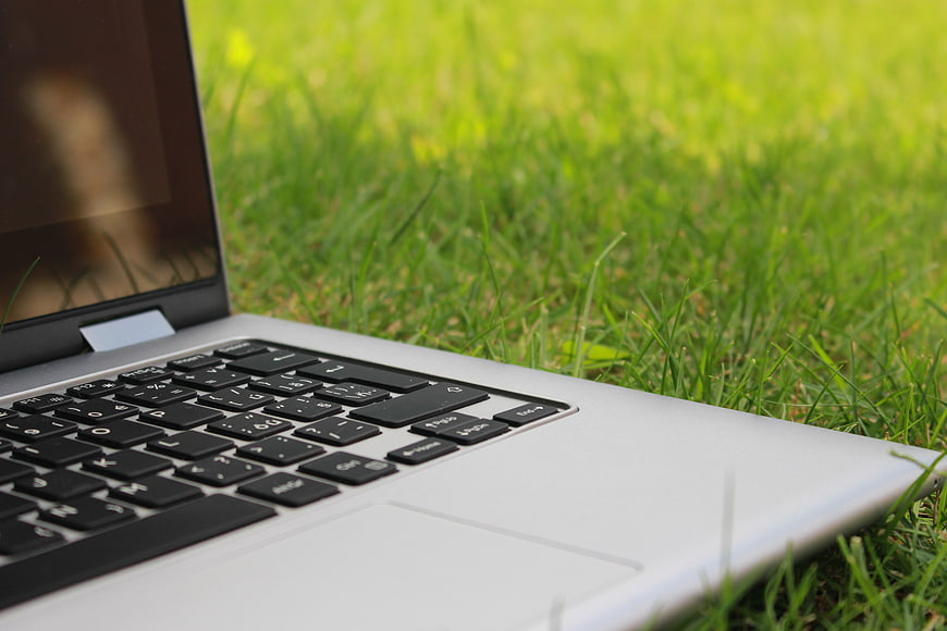 Silver laptop on green grass in nature