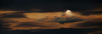 Dramatic Full Moon Rising Above Dark Clouds at Dusk