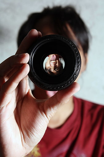 Woman holding camera lens with reflection of face