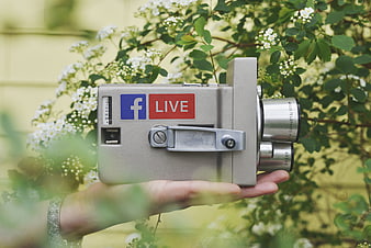 Hand holding vintage film camera with Facebook Live sticker