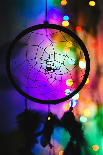 Silhouette of a dreamcatcher against colorful bokeh lights