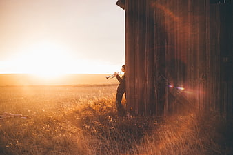 Man playing trumpet in field at sunset