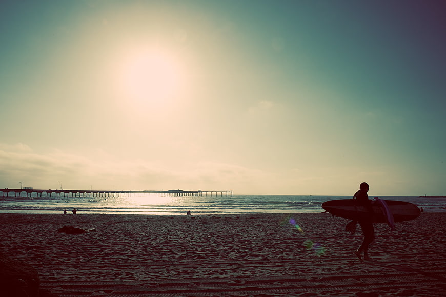 Silhouette of Surfer Walking on Beach at Sunset