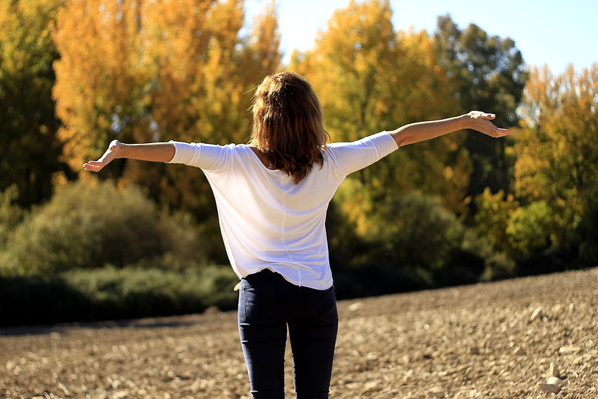 Woman with arms outstretched in autumn field