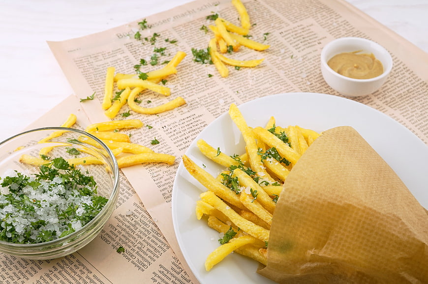 Crispy French Fries with Salt and Mustard on Newspaper