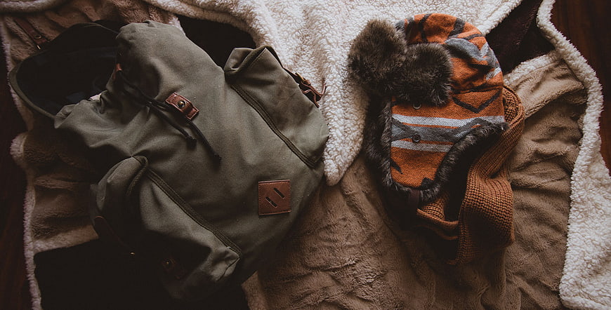 Cozy winter travel gear flat lay with backpack and hat