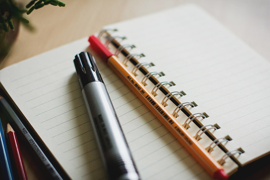 Stationery on spiral notebook with marker and pencil