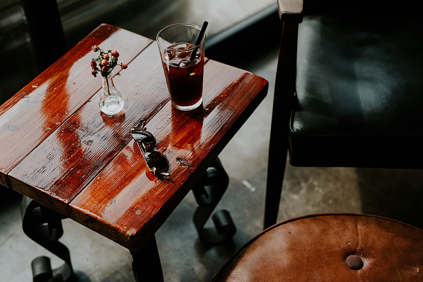 High angle view of iced coffee, sunglasses, and flowers on wooden table