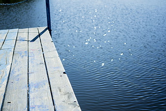 Weathered Wooden Dock Edge Over Sparkling Blue Water