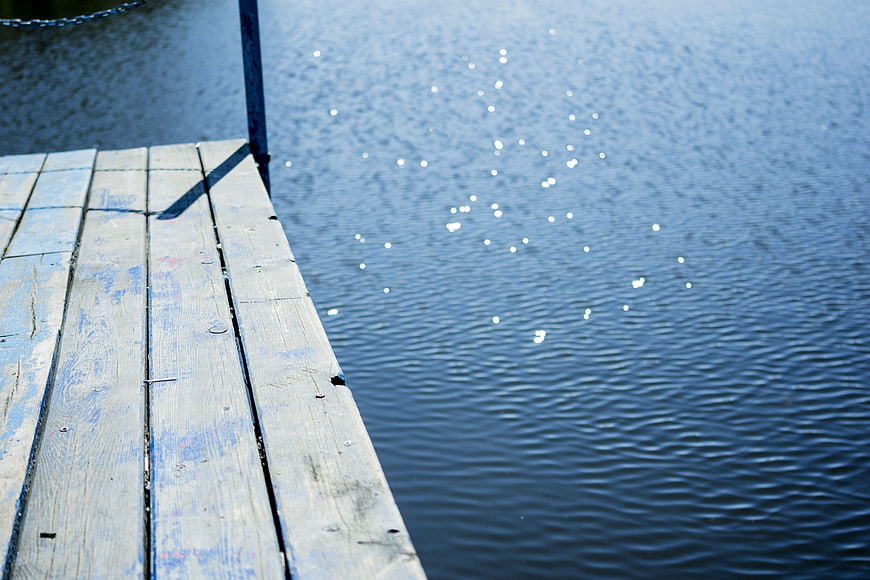 Weathered Wooden Dock Edge Over Sparkling Blue Water