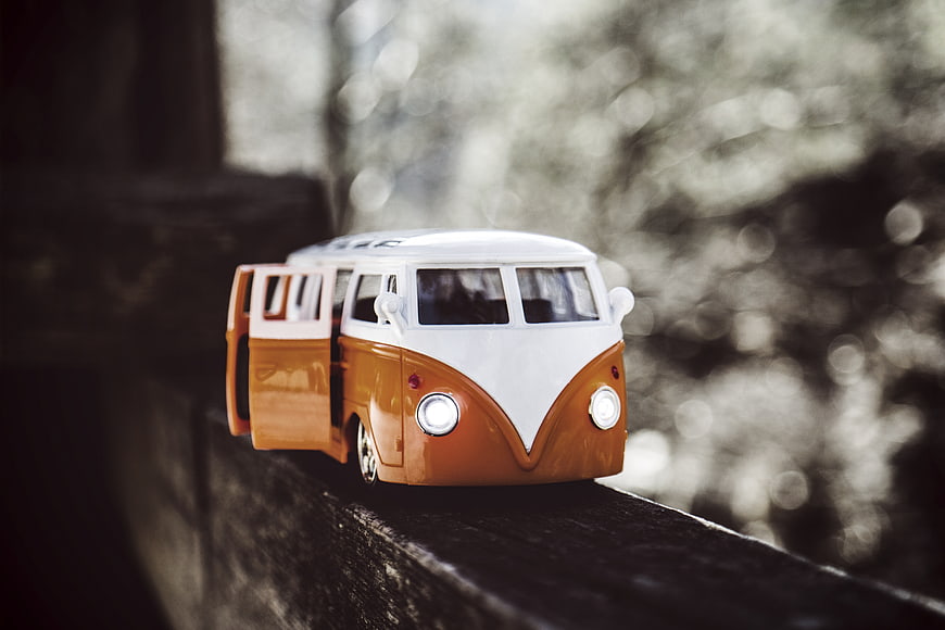 Vintage Orange and White Toy Camper Van on Wooden Surface
