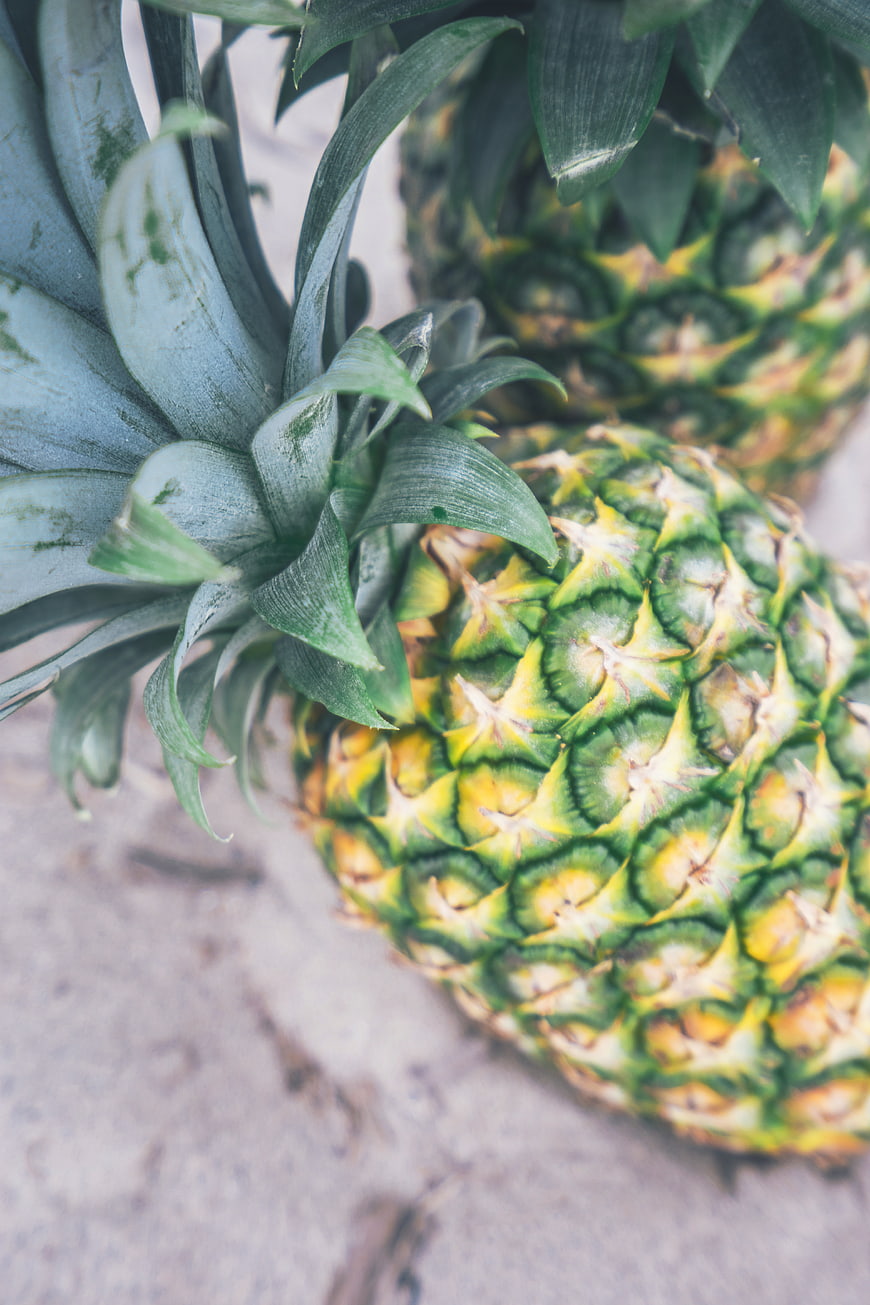 Close-up of fresh pineapples with green leaves on rustic background