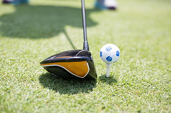 Golf Driver and Ball on Tee on Green Grass