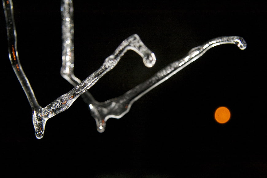 Frozen icicles hanging against a dark background with sunset