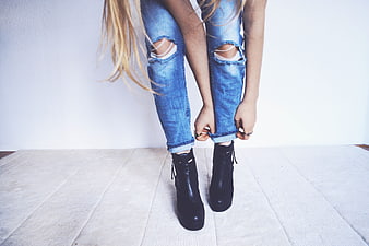 Woman rolling up ripped jeans with black boots