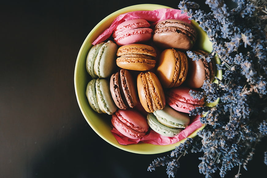 Colorful macarons in a bowl with dried lavender