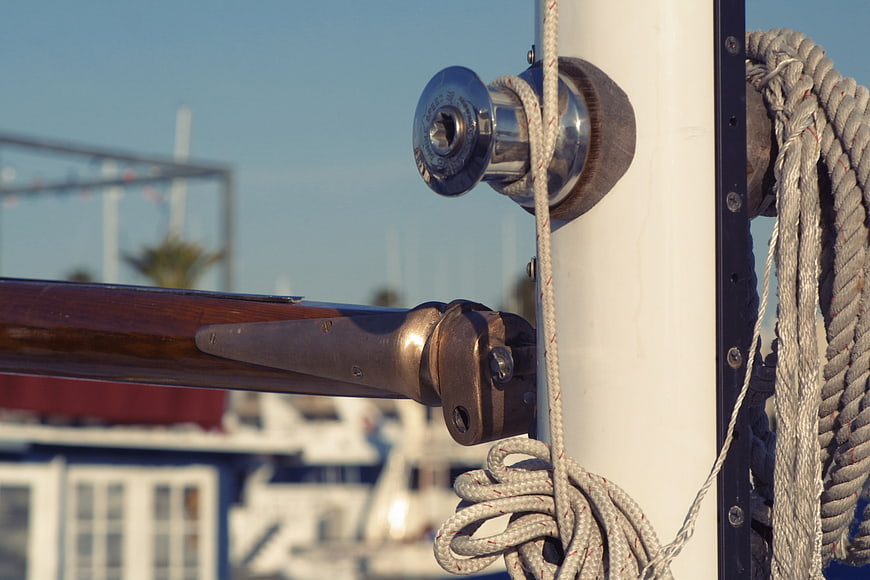 Close-up of sailboat winch, rope, and mast hardware